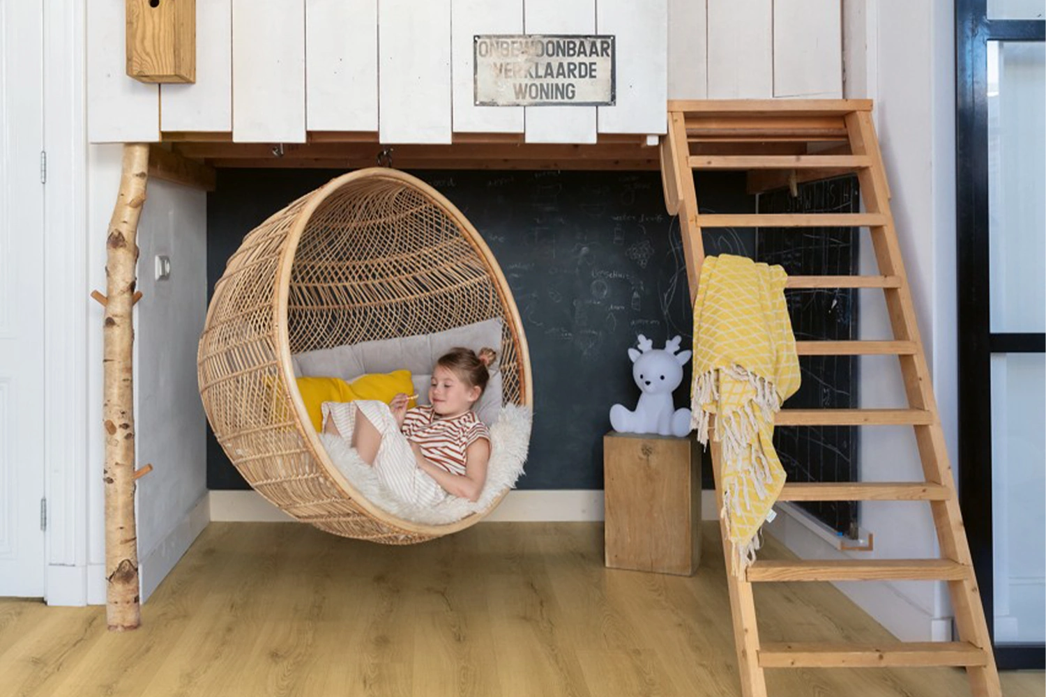 Pokój dziecka z jasną podłogą i wiszącym fotelem rattanowym